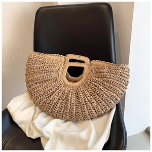 Detail of handmade woven straw bag with thick rope texture on a white fabric surface