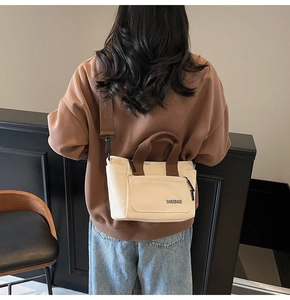 Canvas shopper met bruine riemen gedragen door een model tegen een strakke achtergrond