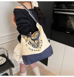 Détail d'un sac cabas en toile beige et bleu marine avec bandoulière réglable