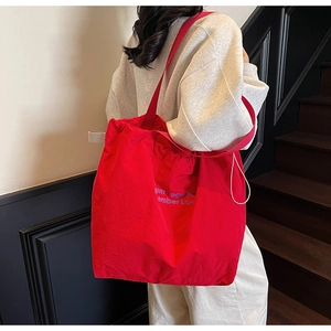 Detailed view of red large canvas tote bag with drawstring closure and purple lettering