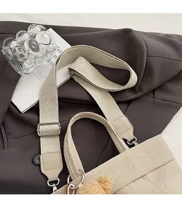 Detail of the adjustable wide fabric shoulder strap and silver metal buckle on the beige tote