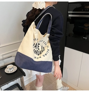Détail du sac cabas en toile montrant les coutures contrastées et l'imprimé texte