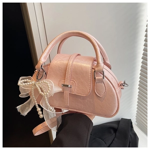 Detail of pink faux leather shell bag with white lace bow and pearl charm accessory