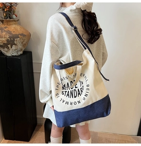Détail du sac cabas en toile bleue et blanche avec bandoulière et texte imprimé