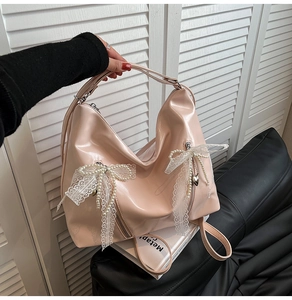 Detail of pink patent leather bag featuring white lace bows and pearl heart charms