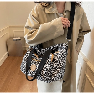 Detailed macro view of large leopard print tote bag with black webbing straps and logo
