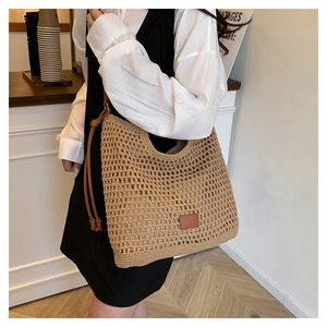 Detail of hollow woven tote bag with a brown leather logo patch and knot shoulder strap