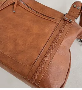 Close-up of brown vintage leather tote with ethnic woven strap and metal zipper detail