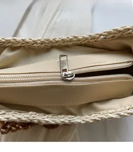 Close-up of a woven straw bag showing the metal zipper closure and soft beige lining