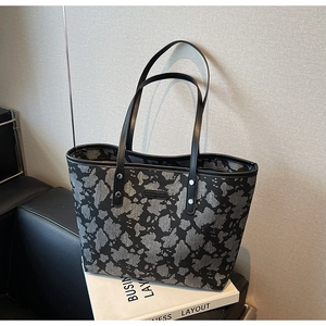 Detailweergave van de tote bag met abstracte bloemenpatronen en zwarte leren riemen