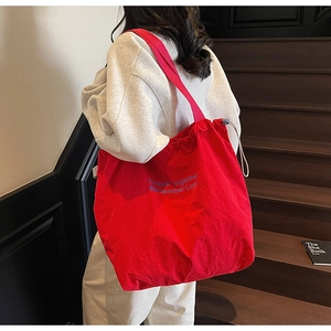 Detail view of large red nylon drawstring tote bag with blue lettering on stairs