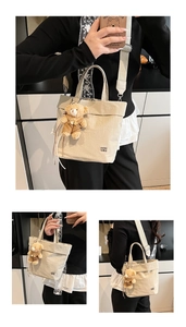 Detail of minimalist beige canvas tote bag with adjustable strap and cute bear charm