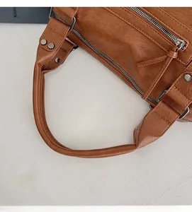 Detail of caramel faux leather bag with vintage fringe zipper and reinforced rivets
