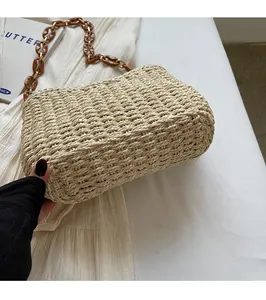 Detail of hand-woven straw bag texture with amber chain strap and gold hardware