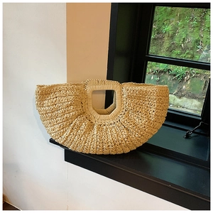 Detail of a handmade semi-circular straw woven tote bag in a natural beige finish