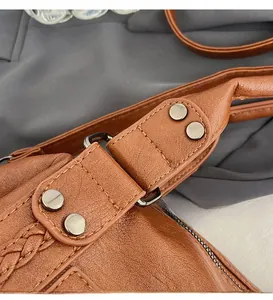 Detail of caramel brown tote bag showing rivet reinforcement and hand-woven stitching