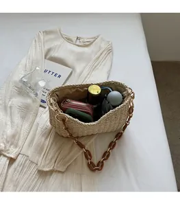 Top view of spacious interior in straw beach bag with resin chain on white dress