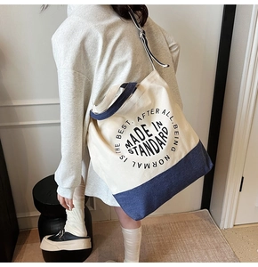 Détail du sac fourre-tout en toile minimaliste avec accents bleus porté par le mannequin