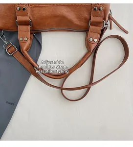 Detail of adjustable shoulder strap and rivet hardware on brown leather motorcycle bag