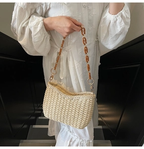 Close-up of handmade beige straw bag featuring amber resin chain and gold metal rings