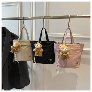 Detailed close-up of textured tote bags in three colors with cute bear pendants