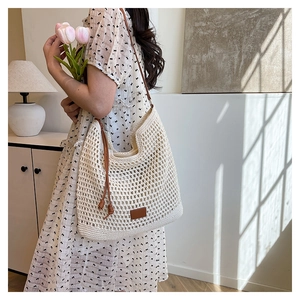 Detail of cream crochet shoulder bag with brown leather patch and side tassels