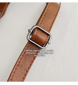 Detail of silver metal adjustment buckle on brown leather strap with reinforced stitching