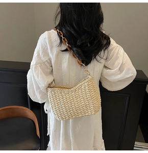 Detail of straw shoulder bag with amber acrylic chain strap on white dress