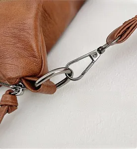Close-up of gunmetal grey hardware hooks and textured brown leather on a vintage tote bag