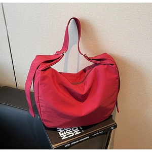 Detailed view of red hobo bag with adjustable wide strap on urban housing books