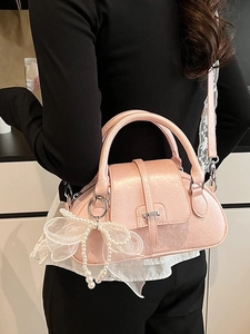 Pink bow shell bag with pearl pendant and lace strap shown on model's shoulder
