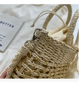 Détail du sac seau en paille beige avec des accents de fils dorés et ferrures brillantes