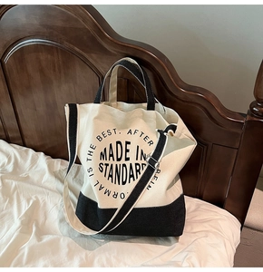 Détail du sac fourre-tout en toile avec sangle réglable et coutures contrastées sur lit