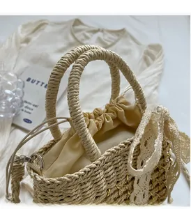 Détail du sac seau en paille avec nœud en dentelle crème et fermeture à cordon