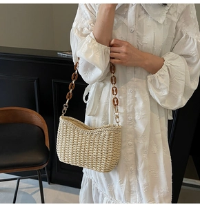 Detail of hand-woven straw bag with amber resin chain strap and gold hardware