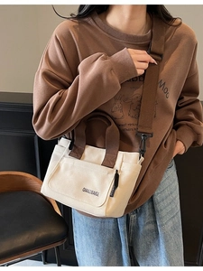 Minimalistische crème canvas crossbodytas met bruine banden gedragen door een model