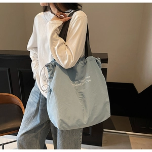 Detail of light blue canvas tote bag with Dream Together Remember Love text and drawstrings