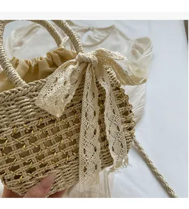 Détail du sac en paille avec chaîne dorée, nœud en dentelle et doublure avec cordon