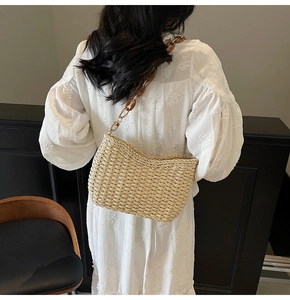 Detail of hand-woven straw shoulder bag with stylish amber resin chain strap on model
