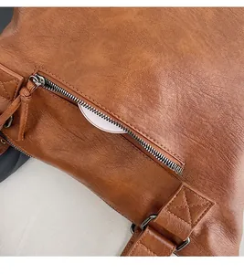 Detail of rear anti-theft zipper pocket on brown lychee texture faux leather tote bag