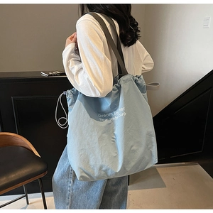 Detail of light blue drawstring tote bag with Dream Together white printed lettering