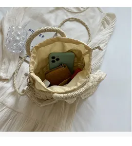 Vue intérieure du sac seau en paille montrant l'espace pour téléphone et dentelle blanche