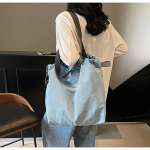 Detail of light blue tote bag with drawstring closure and white printed lettering