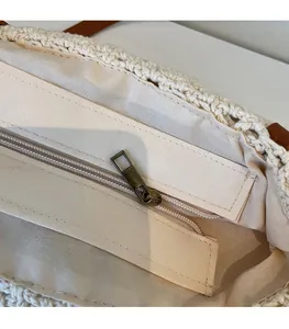 Dettaglio della cerniera in bronzo e fodera in cotone della borsa tote beige all'uncinetto