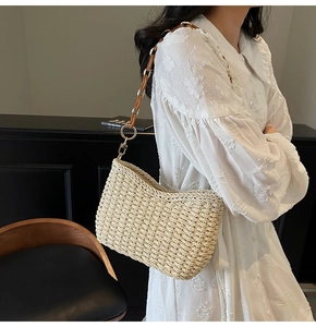Detail of beige straw shoulder bag with unique gold metal and brown resin chain strap