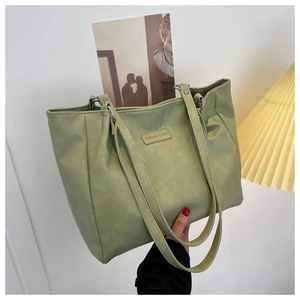 Macro view of light green PU leather tote bag with lychee texture and fashion label