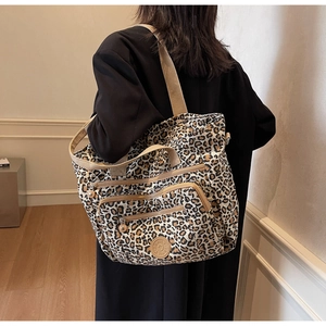 Detailed view of leopard print tote bag with multiple zippers shown on a model
