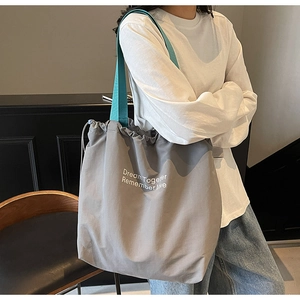 Detail of grey canvas tote bag with drawstring closure and blue wide shoulder strap