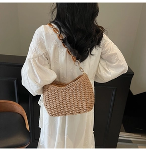 Detail of woven straw shoulder bag with amber acrylic chain strap on a white dress model