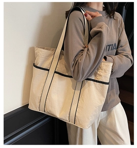Close-up of functional side pocket on beige tote bag during urban outdoor use